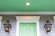 Closeup Of Green And White Door Entrance Of Home Or House Architecture Detail In New Orleans, Louisiana With Gas Lamp Lanterns