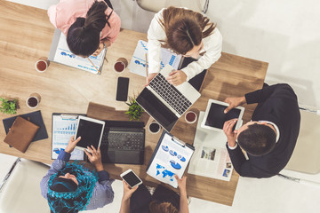 Top view of businessman executive in group meeting with other businessmen and businesswomen in modern office with laptop computer, coffee and document on table. People corporate business team concept.