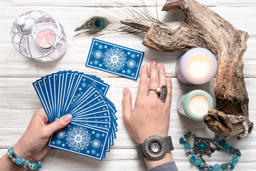 Wall Mural - Fortune teller woman and a blue tarot cards over white wooden table background.