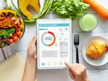 Calories Counting , Diet , Food Control And Weight Loss Concept. Woman Using Calorie Counter Application On Tablet At Dining Table With Fresh Vegetable Salad