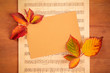 Autumn background with vibrant fall leaves with a card and sheet music, a design template for a flier, invitation, or gift card with copy space