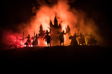 Medieval battle scene with cavalry and infantry. Silhouettes of figures as separate objects, fight between warriors on dark toned foggy background with medieval castle.