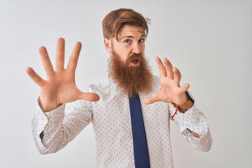 Canvas Print - Young redhead irish businessman standing over isolated white background afraid and terrified with fear expression stop gesture with hands, shouting in shock. Panic concept.