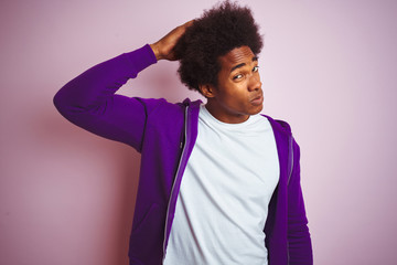 Young african american man wearing purple sweatshirt standing over isolated pink background confuse and wondering about question. Uncertain with doubt, thinking with hand on head. Pensive concept.