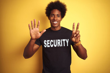 Sticker - American safeguard man with afro hair wearing security uniform over isolated yellow background showing and pointing up with fingers number seven while smiling confident and happy.