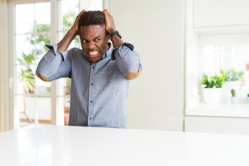 Canvas Print - Handsome african american man on white table suffering from headache desperate and stressed because pain and migraine. Hands on head.