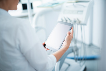 Wall Mural - Female dentist is reading on digital tablet