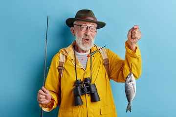 Wall Mural - excited senior man showing his fash to the camera, close up photo.isolated blue background, studio shot