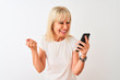 © Krakenimages.com - Middle age woman using smartphone standing over isolated white background screaming proud and celebrating victory and success very excited, cheering emotion