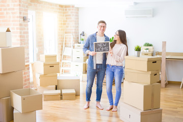 Poster - Beautiful young couple hugging in love and holding blackboard moving to a new home, smiling happy for new apartment