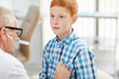 © Seventyfour - Portrait of senior doctor using stethoscope listening to heartbeat and breathing of cute red haired boy during consultation in child healthcare clinic, copy space