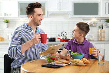 Canvas Print - Dad and son having breakfast together in kitchen