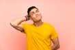 © luismolinero - Young man with yellow shirt over isolated pink wall having doubts and with confuse face expression