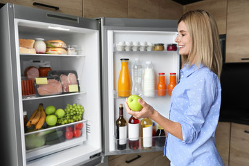 Sticker - Woman with apple near refrigerator in kitchen