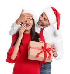 Wall Mural - Young man presenting gift to his girlfriend on white background. Christmas celebration