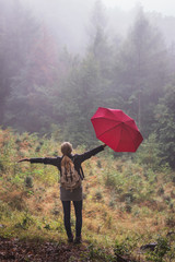 Let the rain makes you happy. Woman with umbrella standing in fog and rain at forest