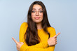 © luismolinero - Teenager girl over isolated blue wall pointing to the laterals having doubts