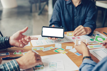 Mock up. Team of website designers who are creative and planning to develop an application on the mobile phone in the office.