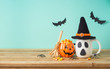 © maglara - Halloween holiday concept with jack o lantern cup, candy corn, witch hat and decorations on wooden table