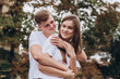 © Stanislav - Happy young couple walks the streets of the city and hold hands. guy and girl in white t-shirts and jeans outdoors. Teenagers cuddling against the backdrop of an autumn tree. Couple close-up portrait