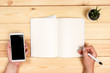 © Nana_studio - Modern workspace with smartphone, paper, notebook and female hands on wooden background. Top view. Flat lay style.