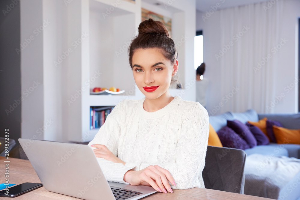 Smiling young attractive woman with laptop sitting at home and studying - obrazy, fototapety, plakaty 