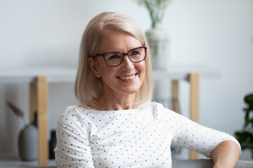 Head shot portrait smiling mature woman looking in distance