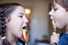 Two Children Licking A Colorful Big Lollipop