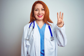 Sticker - Young redhead doctor woman using stethoscope over white isolated background showing and pointing up with fingers number three while smiling confident and happy.