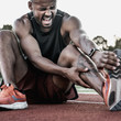 © InsideCreativeHouse - Tired sportsman suffering from knee pain at the stadium track
