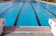Startblöcke am Beckenrand von einem Schwimmbad. Die Blöcke tragen die Nummer drei und vier. Die Startblöcke werden für Schwimmwettbewerbe genutzt .