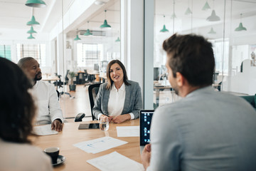 Smiling businesswoman talking with colleagues during an office meeting