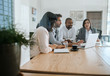 © mavoimages - Businesspeople working on a laptop inside of an office boardroom