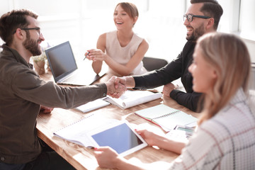 Poster - smiling business partners shaking hands at a business meeting.