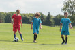 © LIGHTFIELD STUDIOS - curly boy playing football with friends on green grass