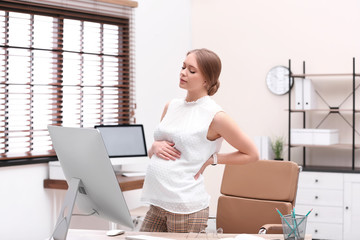 Poster - Young pregnant woman suffering from pain while working in office