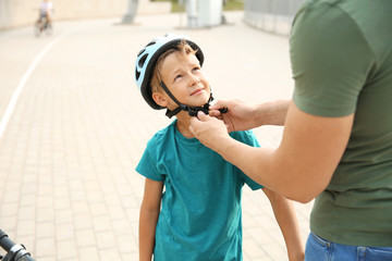 Wall Mural - Father helping his son to put on helmet before riding bicycle outdoors