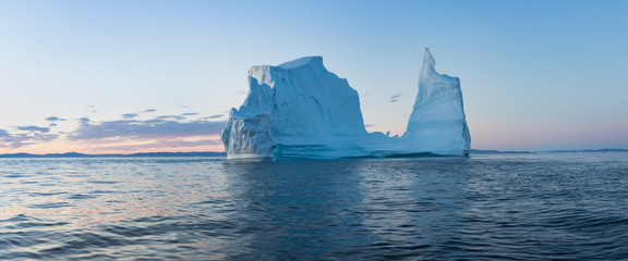 Wall Mural - Iceberg at sunset. Nature and landscapes of Greenland. Disko bay. West Greenland. Summer Midnight Sun and icebergs. Big blue ice in icefjord. Affected by climate change and global warming.