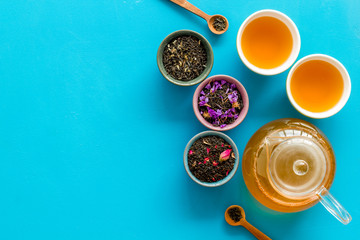 Wall Mural - Cups, teapot, dry tea on blue background top view mockup