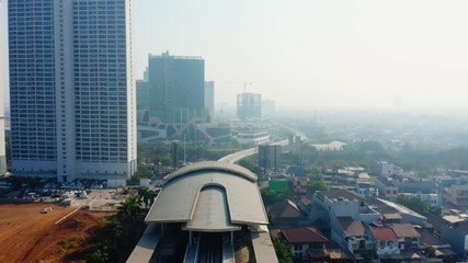 Wall Mural - JAKARTA, Indonesia - September 10, 2019: Aerial view of Jakarta MRT station on the elevated track in misty morning. Shot in 4k resolution from a drone flying forwards