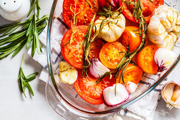 Poster - Baked tomatoes with garlic, onions and rosemary in glass oven dish, top view.