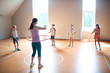 © zinkevych - PE teacher wearing leggings teaching children to use hula-hoop