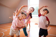 © zinkevych - Smiling teacher helping girl stretching body at PE lesson