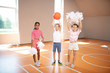 © zinkevych - Little cute cheerleaders standing near classmate with ball