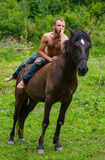Fototapeta Konie - man with a naked torso riding horse