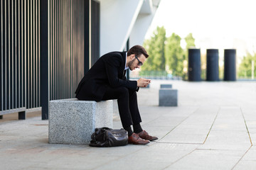 Wall Mural - Modern young man playing on phone, browsing mobile news. Gadget Dependence.