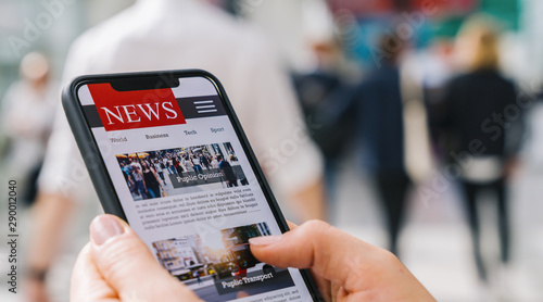 Online news on a mobile phone. Close up of businesswoman reading news or articles in a smartphone screen application. Hand holding smart device. Mockup website. Newspaper and portal on internet.