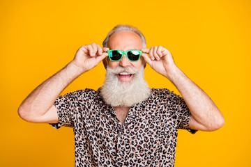 Photo of rejoicing old man staring into camera through his glasses while isolated with yellow background