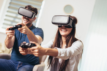 Young happy couple playing video games virtual reality glasses. Couple having fun with new trends technology.