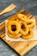 Canvas Print - Fried onion rings on wooden cutting board